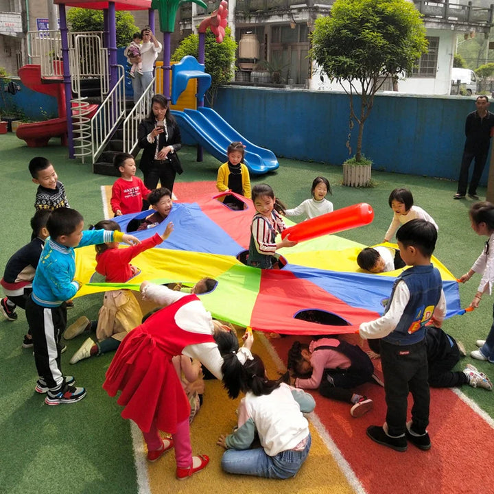 Children playing with a colorful parachute in an outdoor playground.