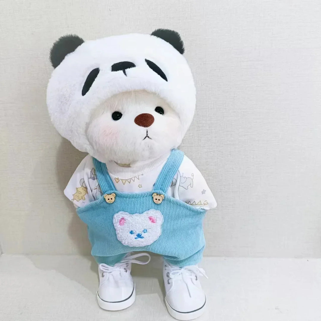 Stuffed toy panda bear wearing a blue outfit with a heart design on a light gray background.