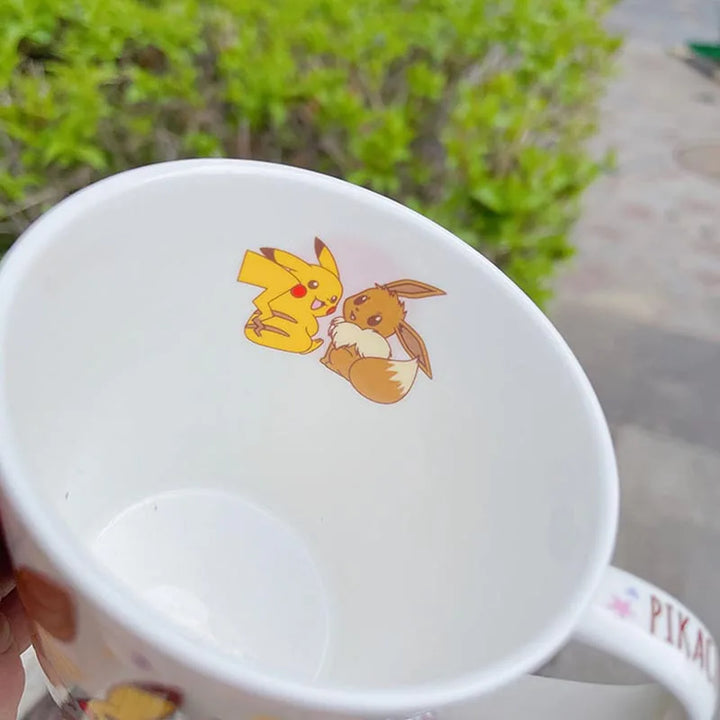 White mug with cartoon characters on a blurred green outdoor background.