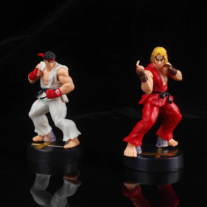 Two action figure statues on black bases against a dark background.