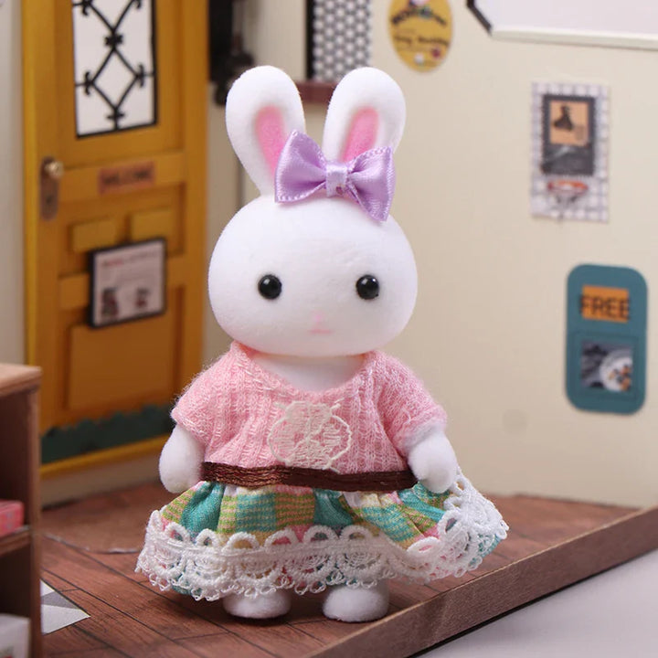 Plush toy rabbit in a pink dress with a bow on a wooden surface.