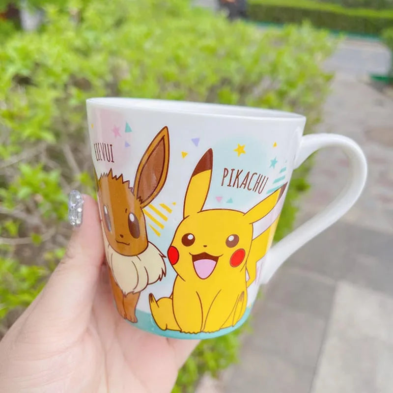Mug with Pikachu and Eevee design held by a hand outdoors.
