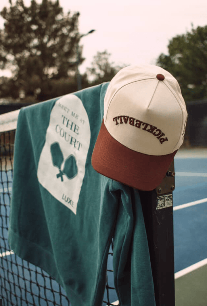 Tennis cap and towel on a racket on a tennis court