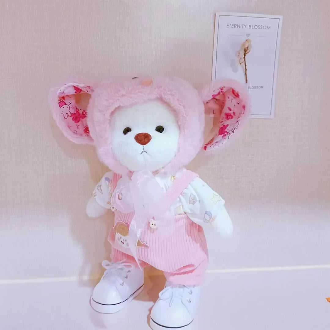 Plush toy bear in a pink outfit with floral ears on a light background.