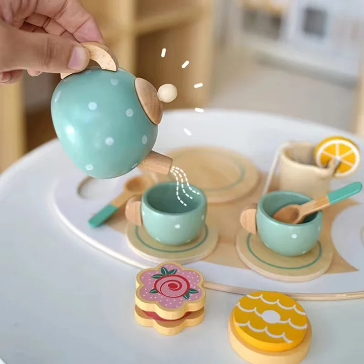 Wooden tea set with teapot, cups, and cookies on a white surface.