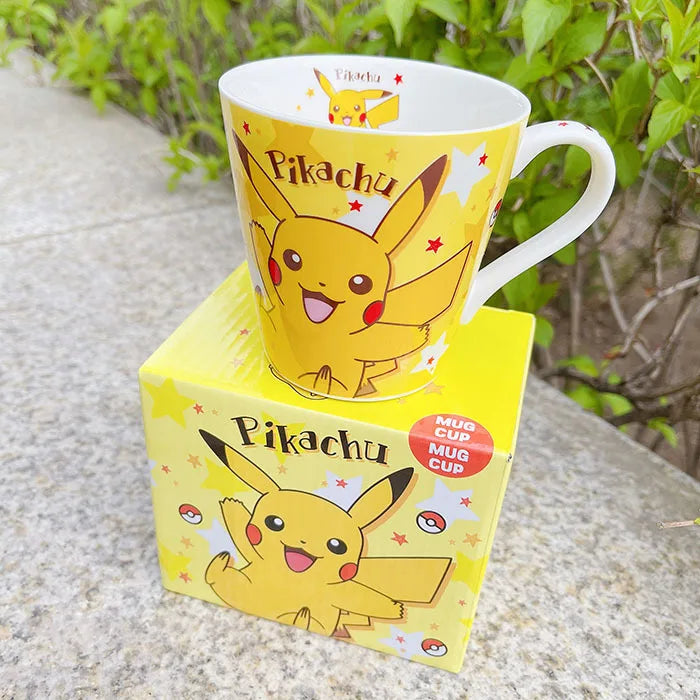 Pikachu mug with matching box on a stone surface with greenery in the background.