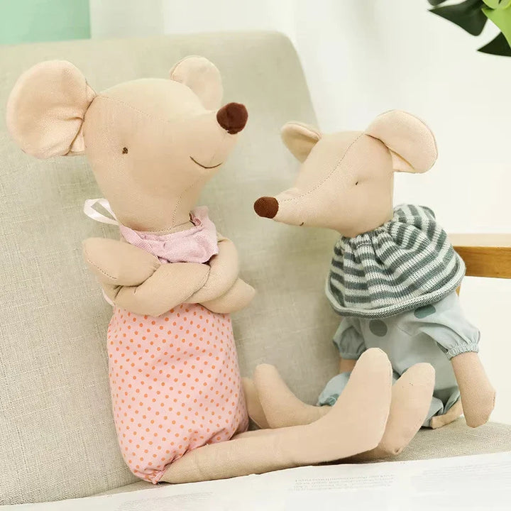 Two plush mouse toys sitting on a couch, one in a pink outfit and the other in a striped outfit.