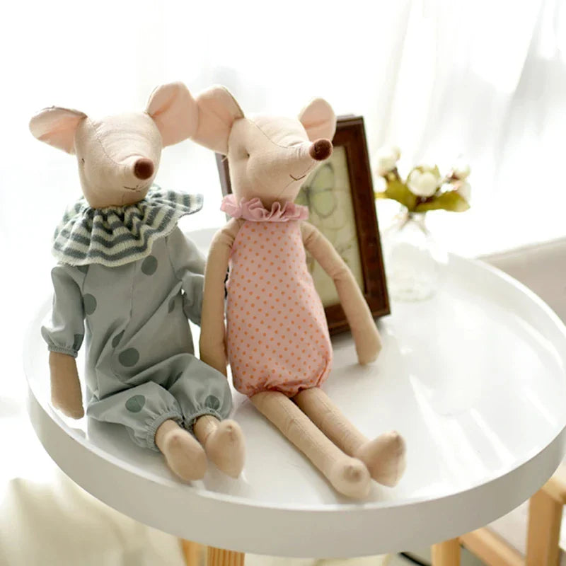 Two plush mouse toys sitting on a small round table with a blurred background.