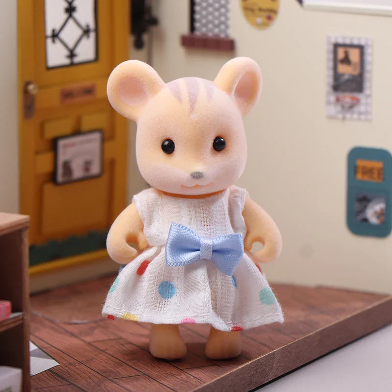 Plush toy mouse in a white dress with colorful polka dots and a blue bow, standing on a wooden floor.