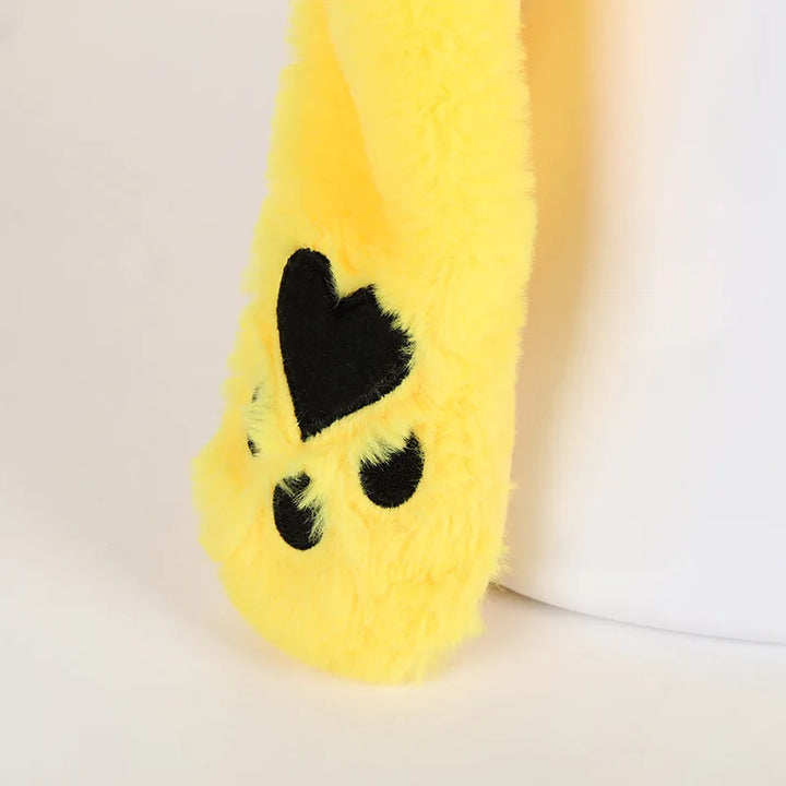 Yellow plush toy resembling a banana with a black heart on a white background.