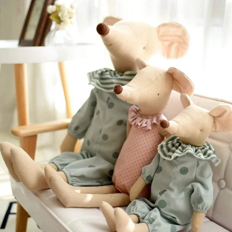 Three plush toys resembling mice in polka dot outfits sitting on a chair.