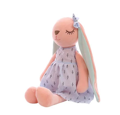Stuffed doll with long ears wearing a patterned dress on a white background.