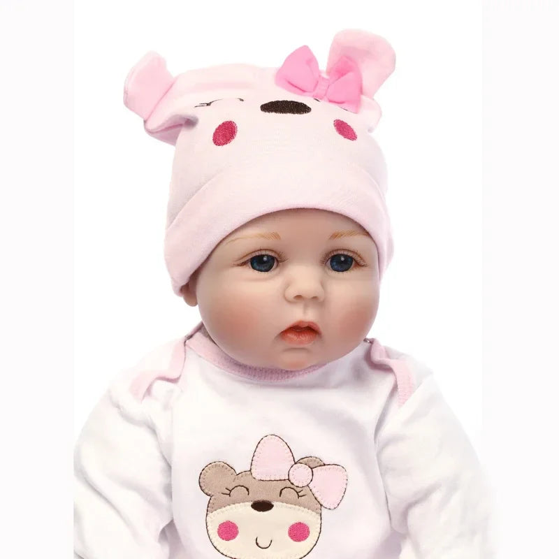 Baby doll wearing a pink hat with ears and a matching outfit on a white background.