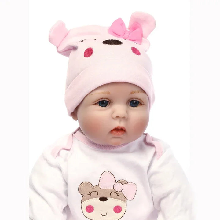 Baby doll wearing a pink hat with ears and a matching outfit on a white background.
