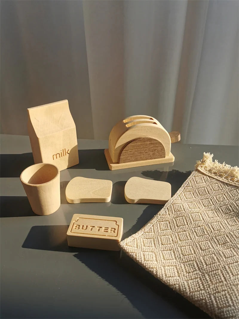 Set of wooden kitchen items including a loaf of bread, a butter block, and a milk carton on a gray surface.