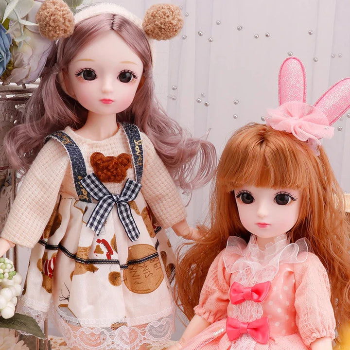 Two dolls with one wearing a dress with a bear design and the other with bunny ears and a pink bow.