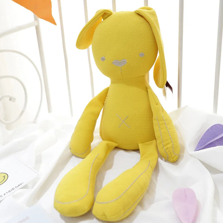 Yellow plush toy with bunny ears on a white surface.