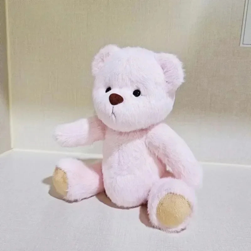 Pink teddy bear on a white surface with a neutral background.
