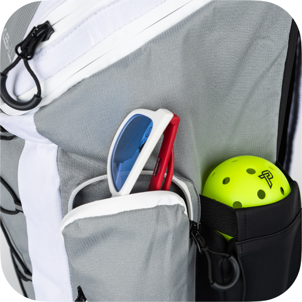 Gray backpack with sunglasses, phone, and yellow ball in front pocket.