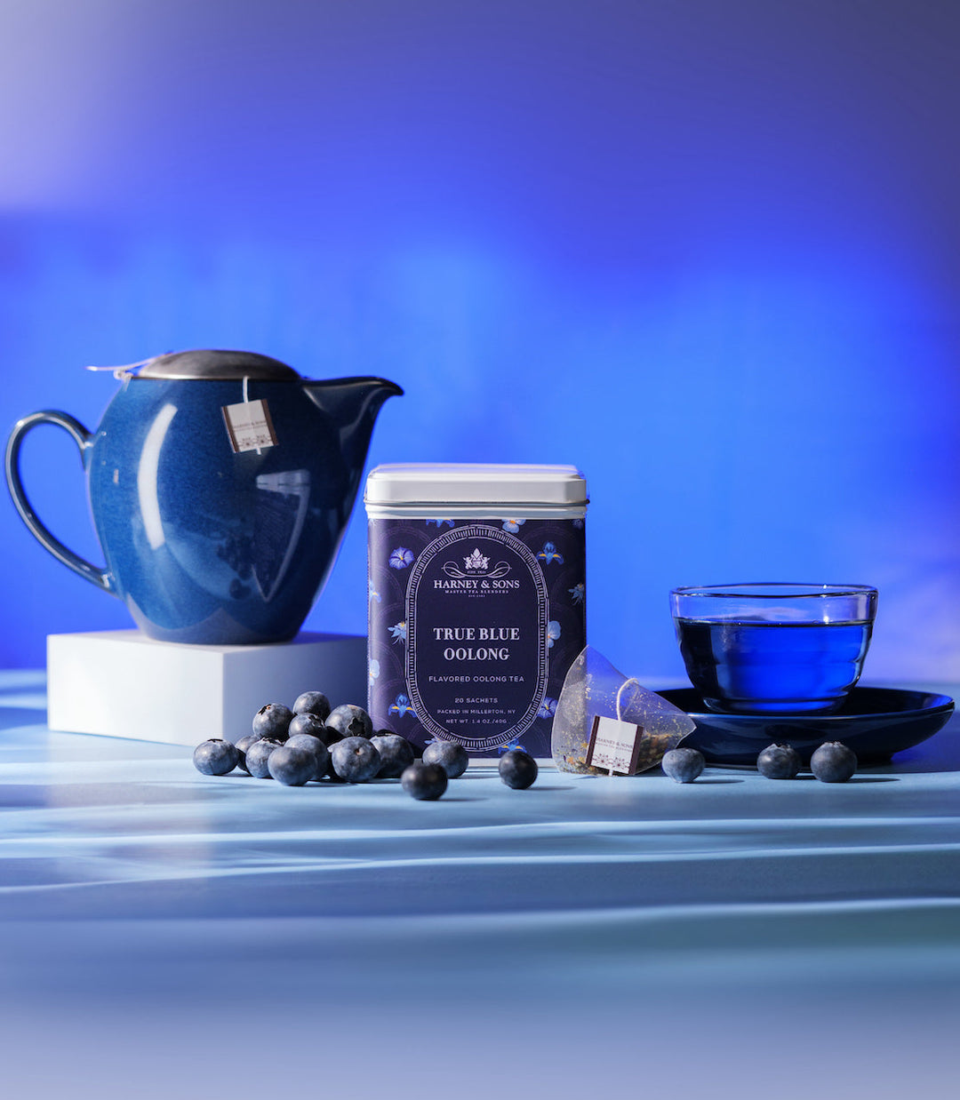 Tea set with a blue pitcher, tea canister, and cup on a blue background.