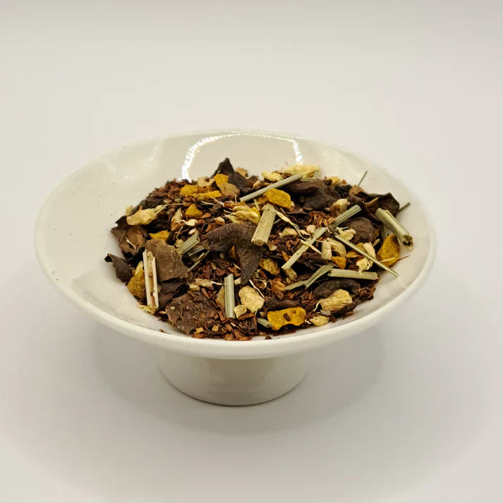 White bowl filled with dried tea herbs on a white background