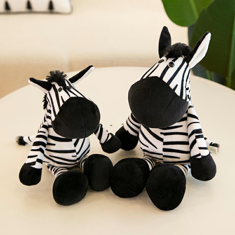 Two plush zebra toys sitting on a light surface with a blurred background.