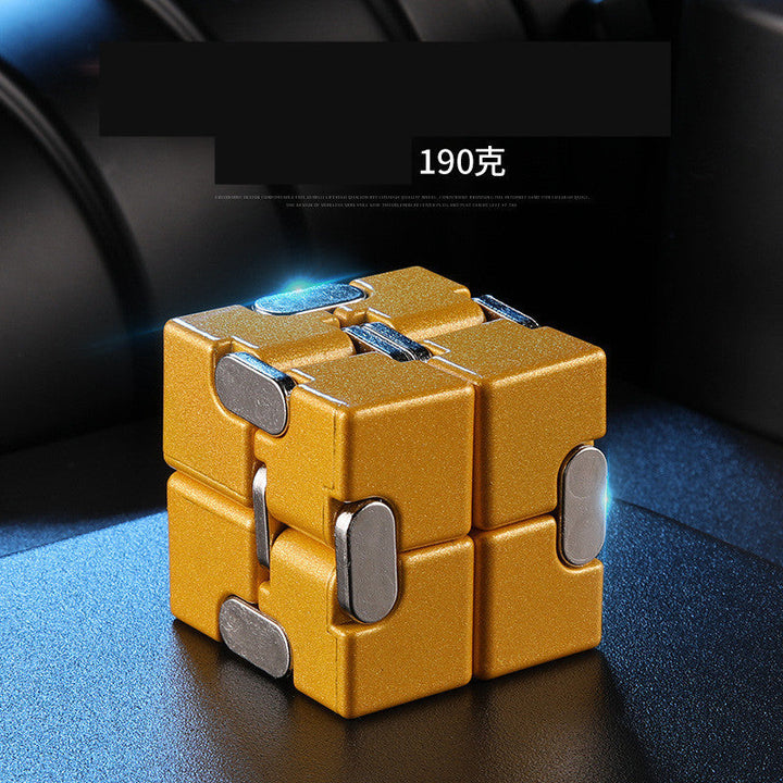 Gold and silver fidget cube on a dark surface.