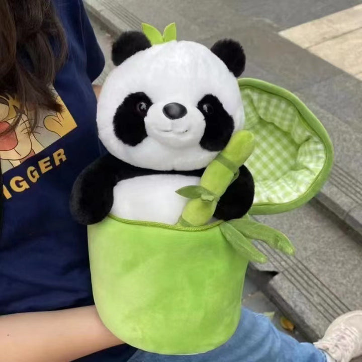 Plush panda toy with a green leafy background held by a person.