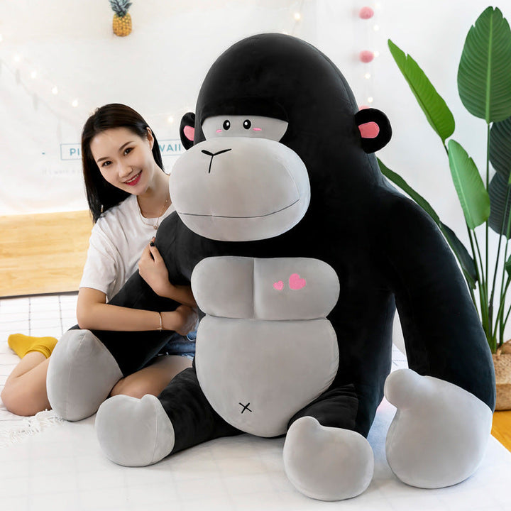 Person holding a large plush monkey toy in a room with plants and decor.