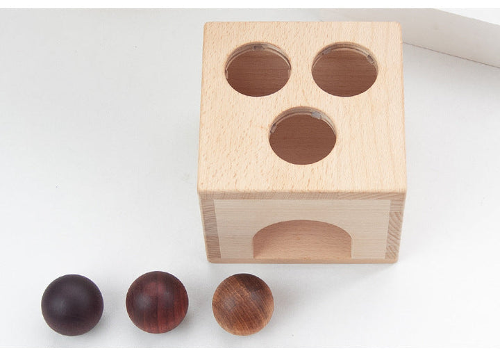 Wooden block with holes and three wooden balls on a white background.