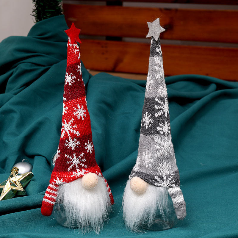 Two Christmas-themed gnomes with knitted hats on a teal fabric background.