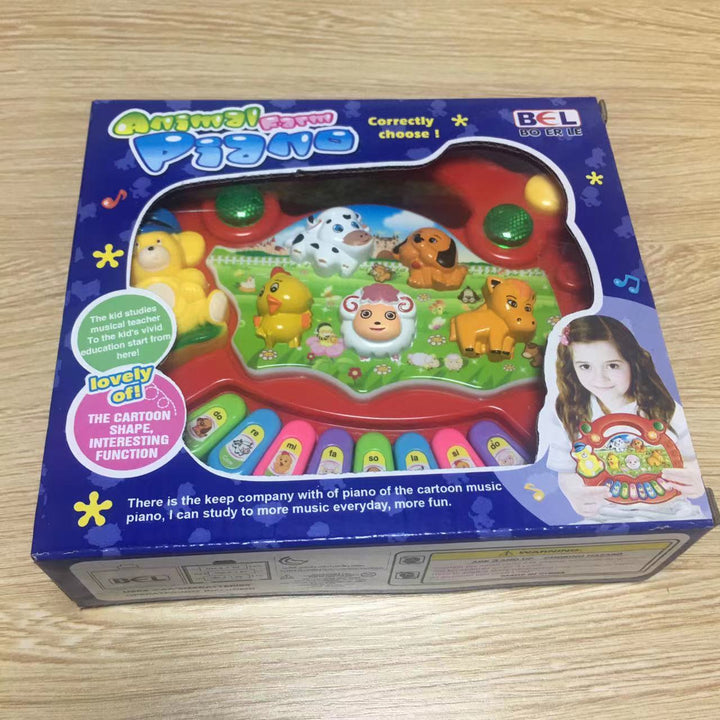 Box of a children's toy piano with cartoon animals on a wooden surface.