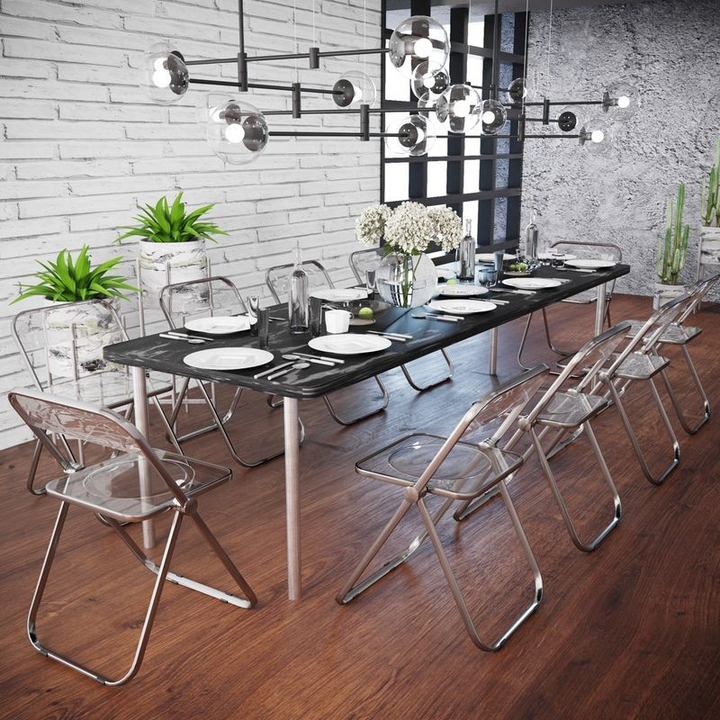 LeisureMod Lawrence Acrylic Folding Chair with Metal Frame Transparent Black at the Table.