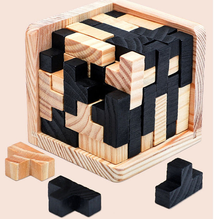 Wooden and black puzzle blocks in a wooden box on a beige background.