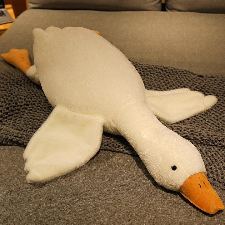 Plush toy goose lying on a textured surface.