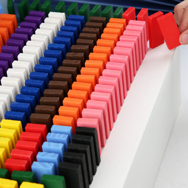 Colorful dominoes set up in a row on a white surface.