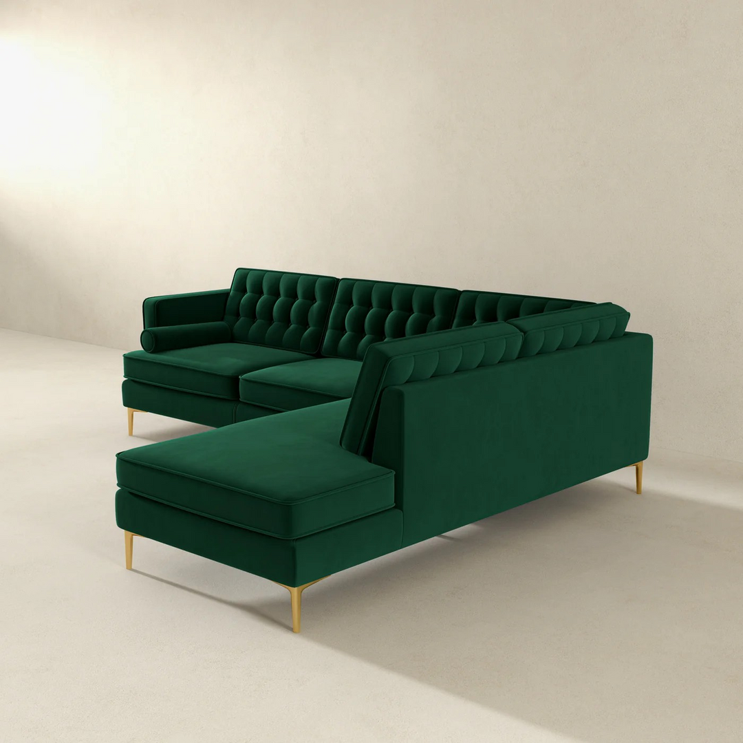 Green velvet sectional sofa on a beige background.