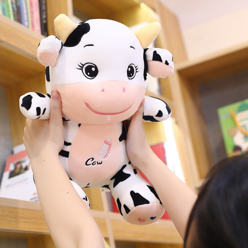 Person holding a plush cow toy in front of a bookshelf.