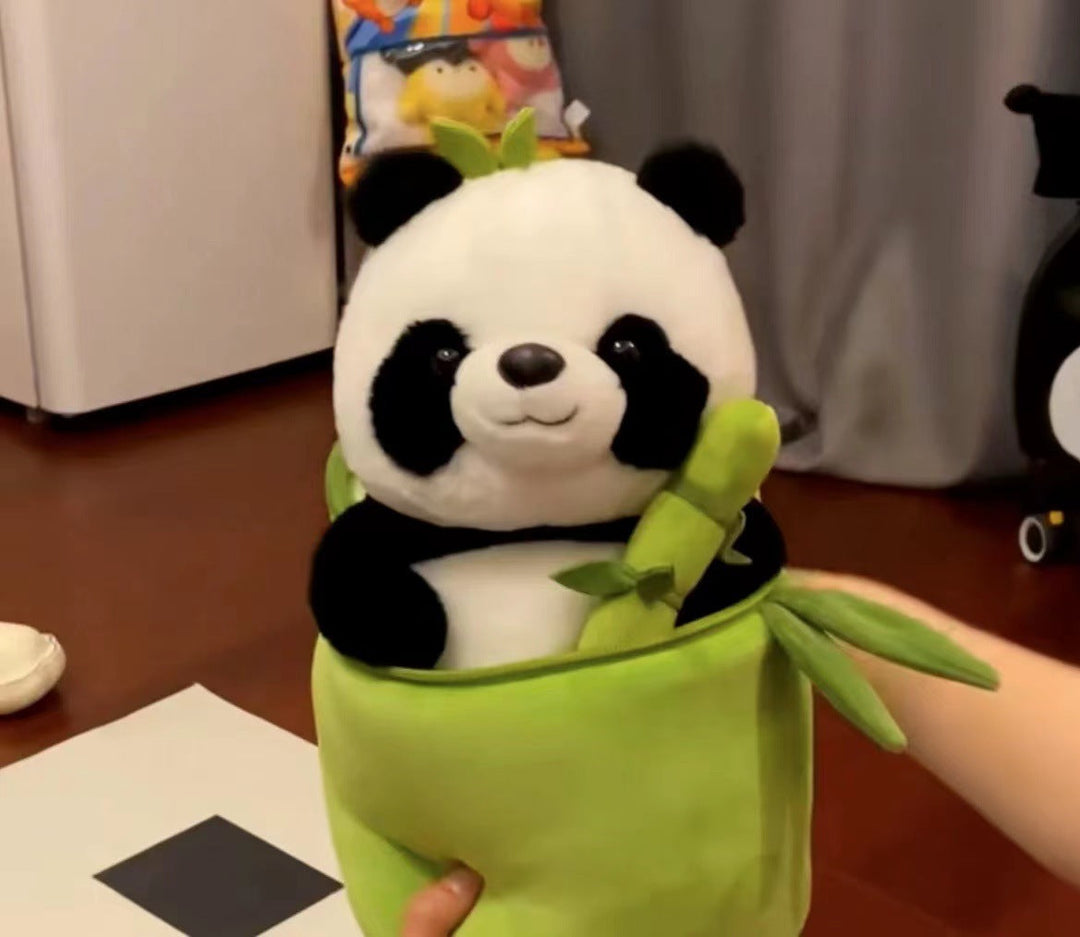Plush panda toy in a green sleeve held by a hand on a wooden floor.