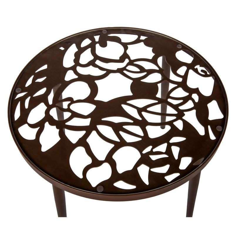 Decorative round metal table with cut-out floral design on a white background.