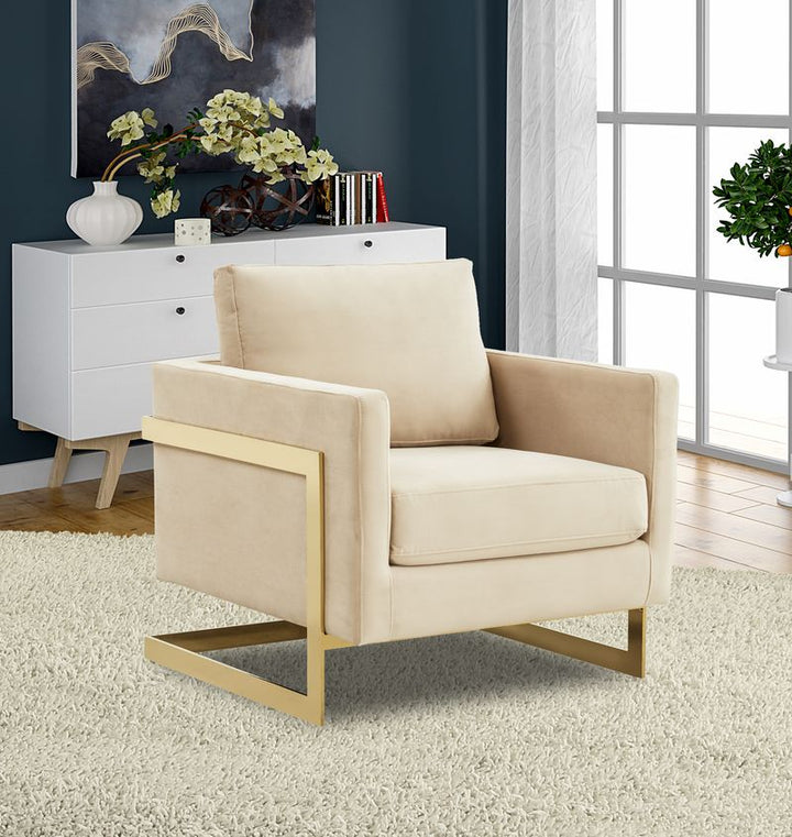 Beige armchair with gold legs in a room with a white cabinet and window.