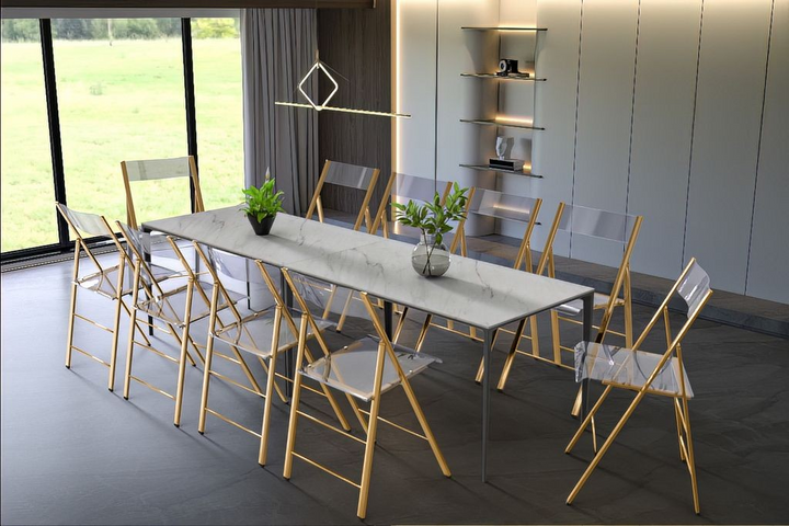 LeisureMod Menno Modern Acrylic Gold Base Folding Chair at the Table.