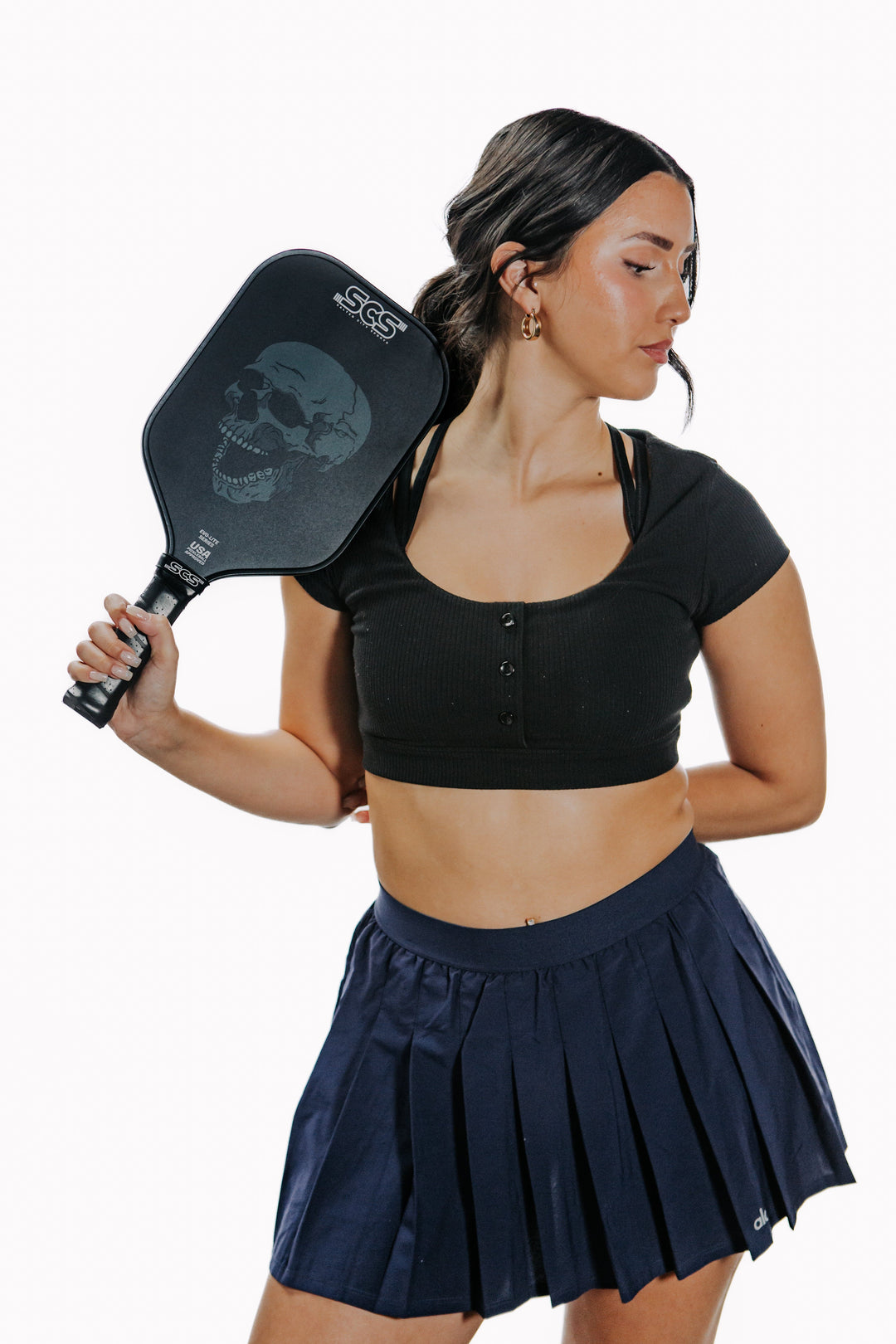Woman holding a pickleball paddle with a white background.
