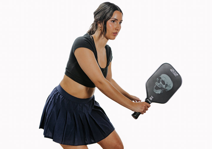 Woman holding a pickleball paddle on a white background.