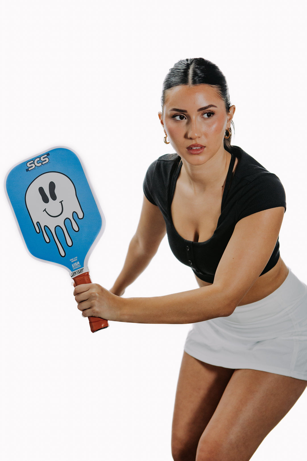 Woman holding a pickleball paddle with a white background.