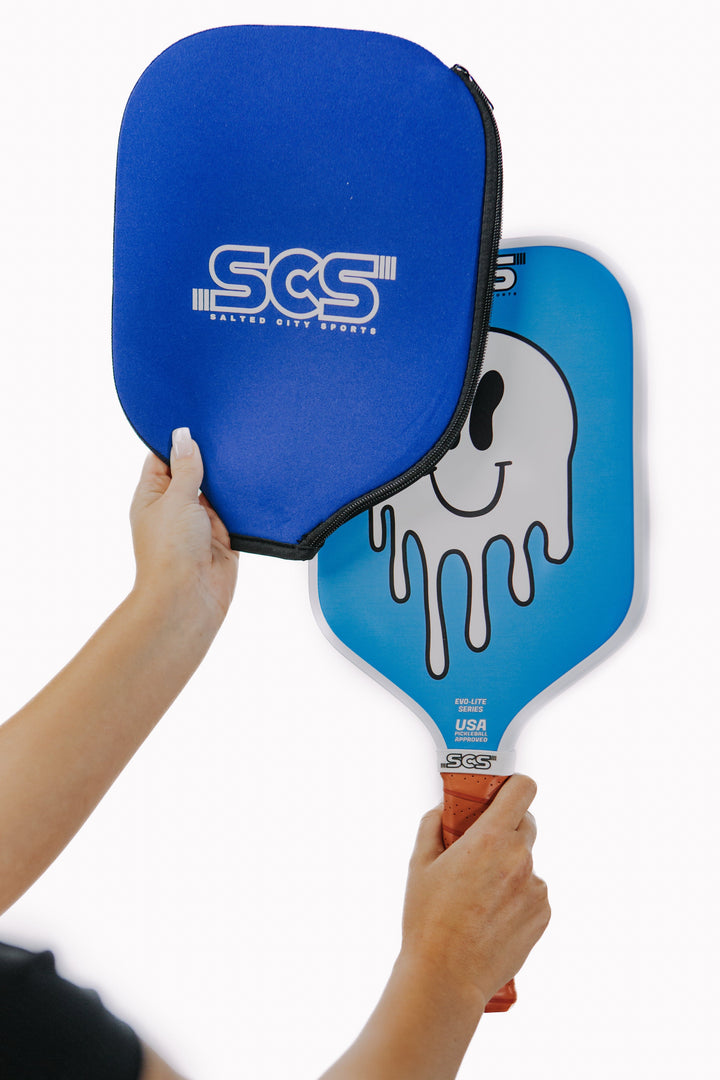 Blue pickleball paddle with SCS branding held by a person against a white background.