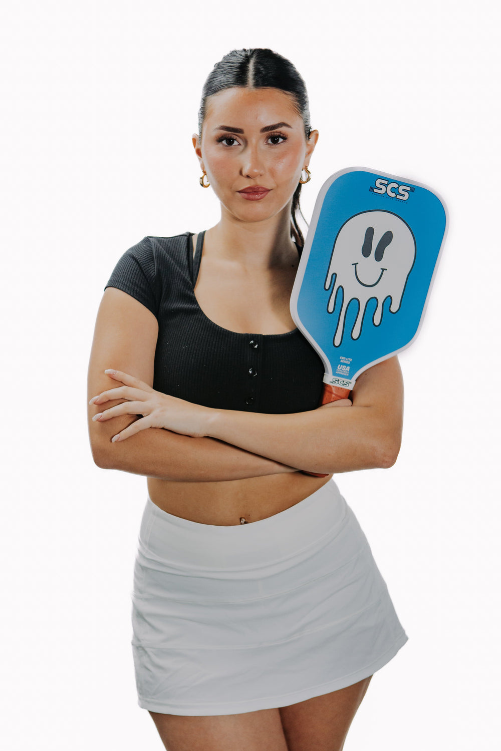 Woman holding a blue pickleball paddle with a smiley face design on a white background.