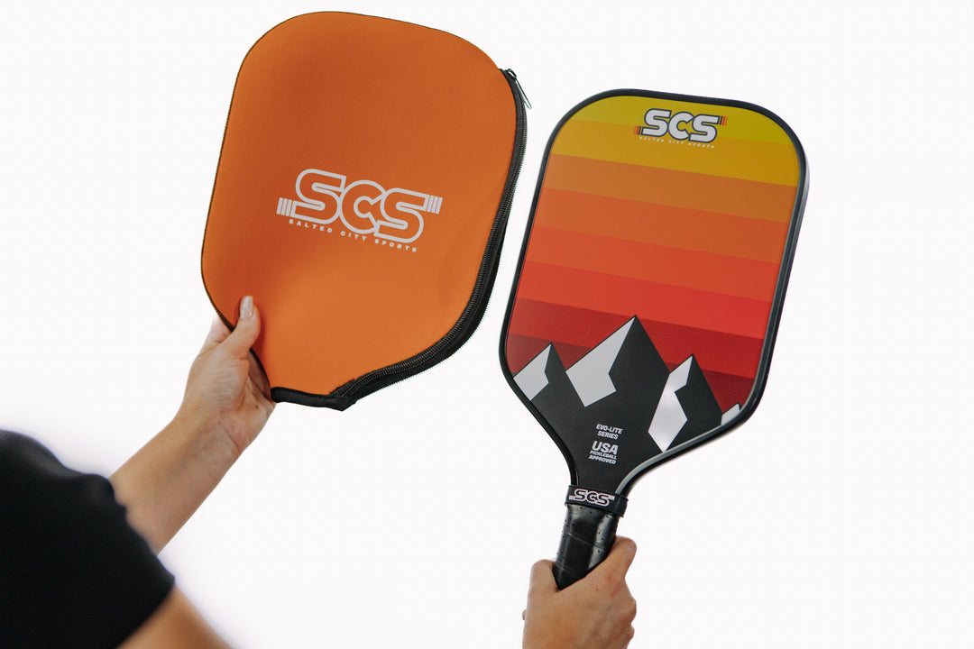 Two pickleball paddles held by a person against a white background, with 'SCS' branding.