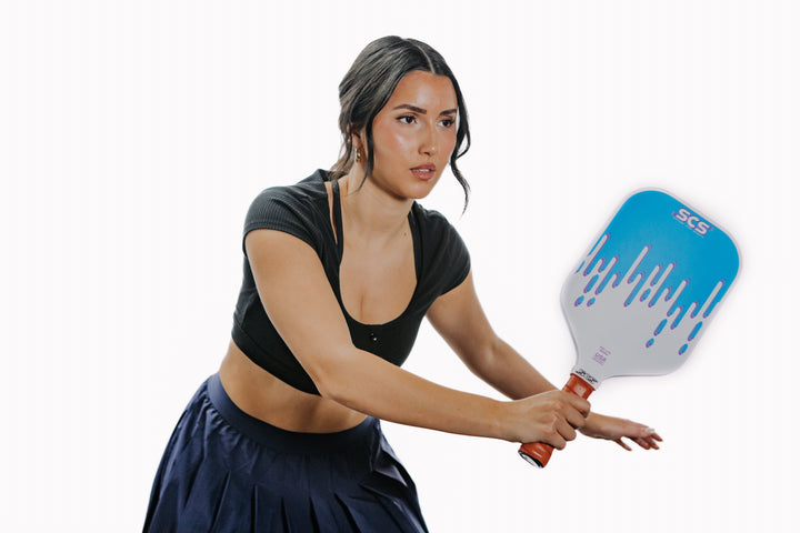 Woman holding a pickleball paddle with SCS branding on a white background.
