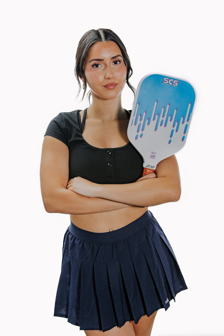 Woman holding a pickleball paddle with a white background.